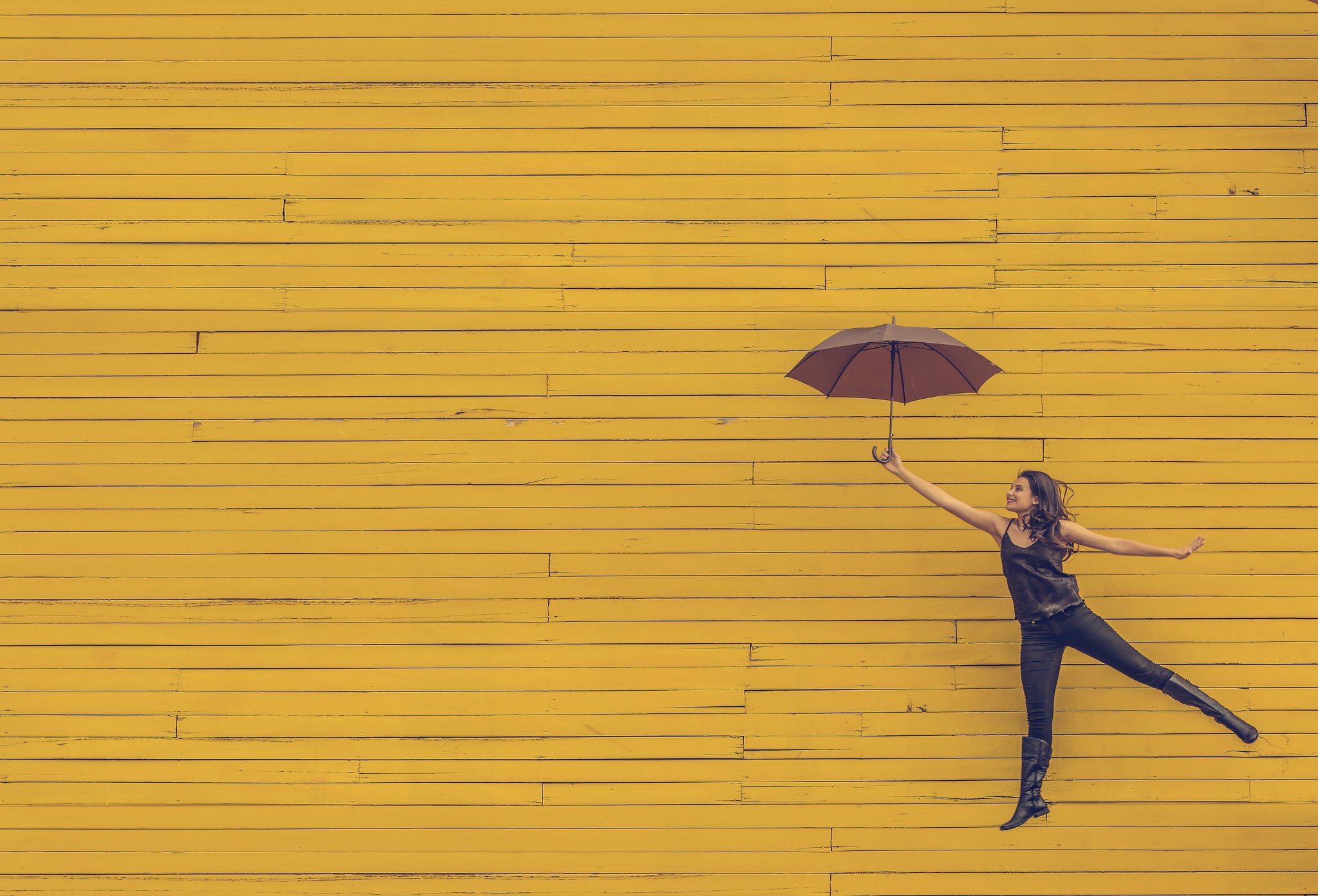 website Woman floating with umbrella against yellow wall