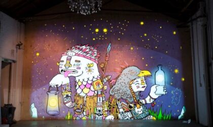 Events An illustration of two characters is projected onto a wall beneath a chandelier. The 2 characters are in profile, each holding a lamp, and have their backs to each other. The projection is incredibly colourful and takes up the the entire wall, which looks to be situated in a theatre or large venue.