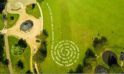 Events We are looking directly down on a park as if from the sky. It is mostly lush green grass with trees to the bottom left and a path with some trees running up the left side. In the centre is a line of poetry written in the grass, spiralling into a circle.