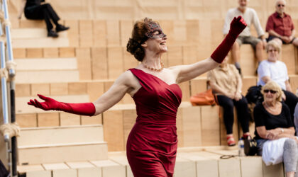 Image of woman acting on stage with audience members in the background