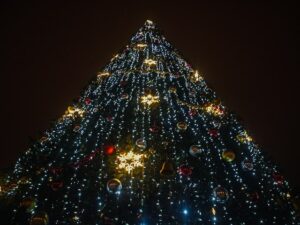 Image of what looks like the shape of a Christmas tree covered in lights and decorations from the perspective of being at the bottom of it looking up.
