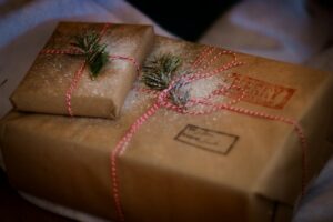 Close up of two gift wrapped presents with red and white parcel string and green foliage