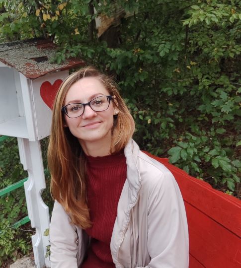 A woman wearing spectacles sat on a red bench