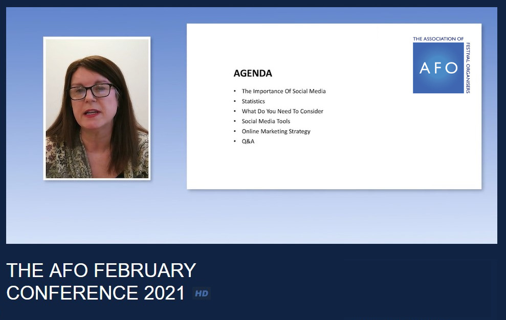 A screenshot of a virtual conference screen. Maddie, a woman with long dark hair and glasses, is presenting next to the slide showing the conference agenda.