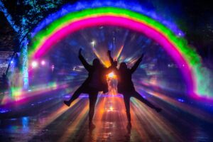 Two people silhouetted against a large rainbow.