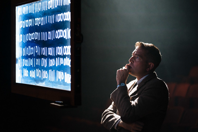Image of man with puzzled look looking at a screen full of codes