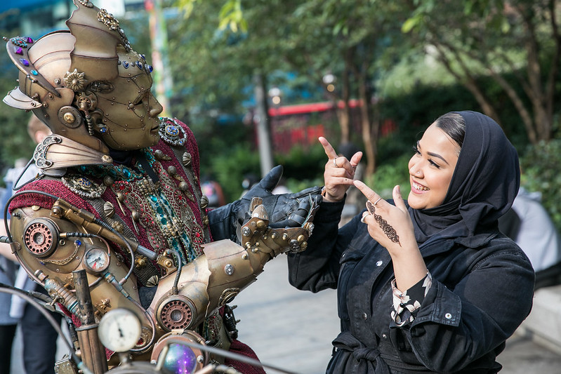 Woman and person dressed as robot looking at each other and smiling.