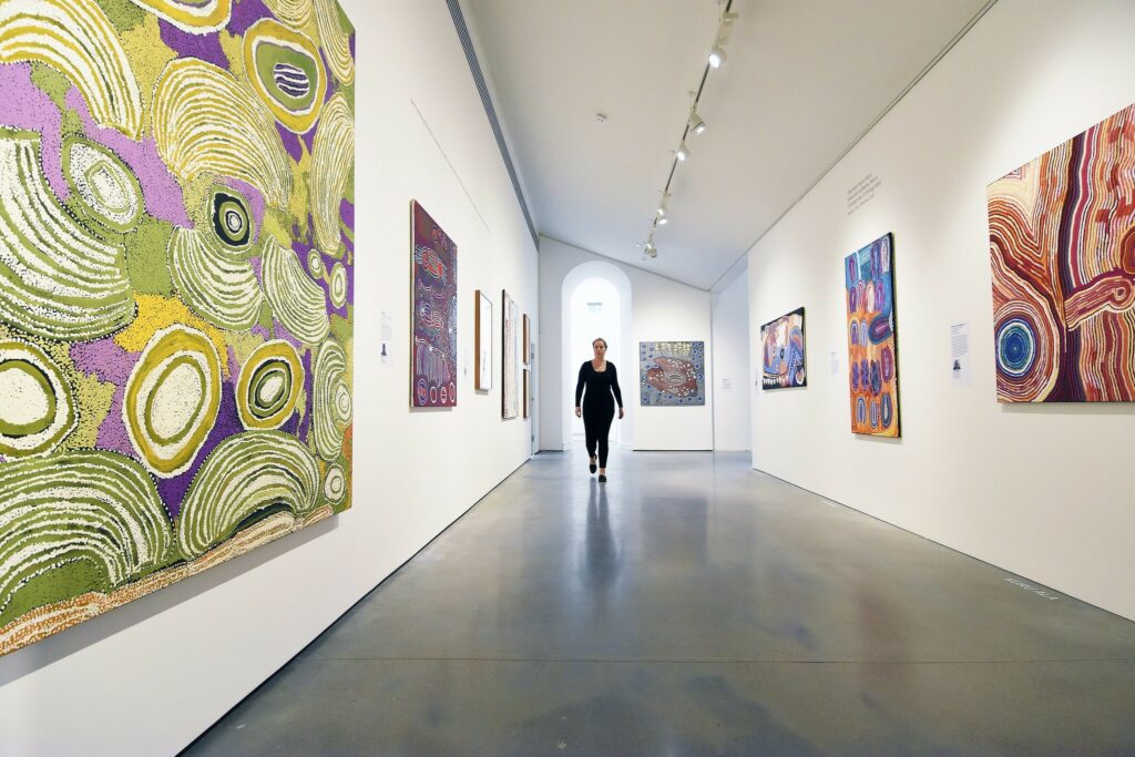 A person walking down a hallway surrounded by artwork hanging on the wall