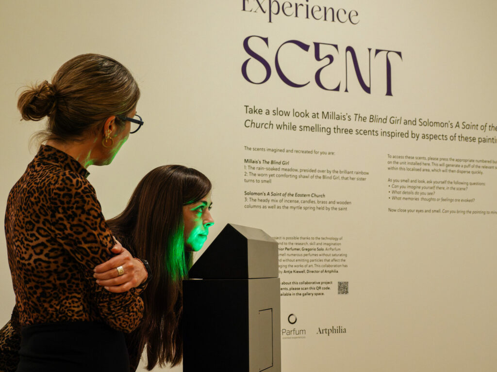 A beige wall presenting a scripture about a project. On left hand side is a lectern with two women standing next to it looking away from the camera.