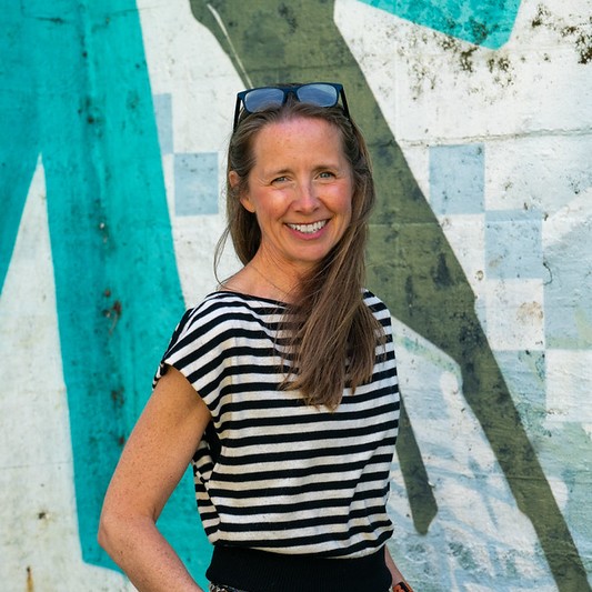 Charlotte smiling and wearing a striped top, against a green patterned wall background.